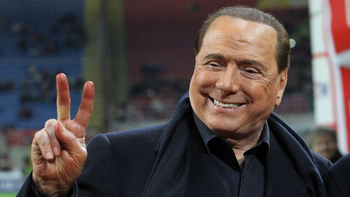 Silvio Berlusconi sorridente allo stadio San Siro fa il segno di vittoria con le dita